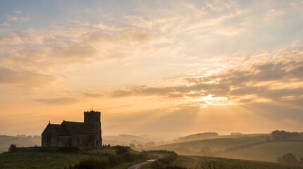 Fototapeta premium Ascension Day peaceful sunset view of an ancient stone church on a hill in a misty countryside landscape with golden sun rays for faith and spirituality