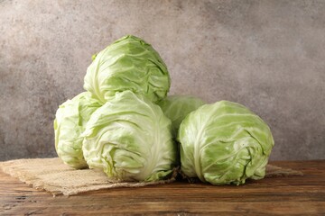 Fototapeta premium Fresh whole cabbages on wooden table against grey background