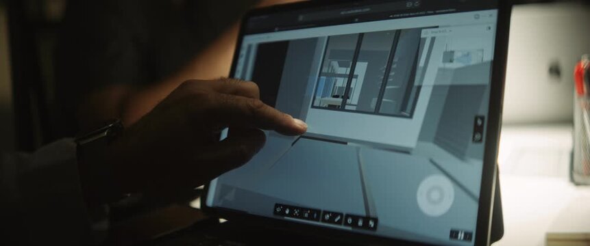 Close-up of a designer or architect working on a digital project using a tablet or touchscreen laptop in a modern workspace with cinematic lighting.