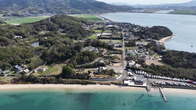 Aerial view of the Itoshima Peninsula featuring a sandy beach, turquoise water, and lush green hills in Itoshima, Fukuoka, Japan.