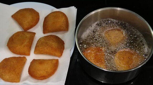 Portuguese rissois being fried in hot oil, a traditional appetizer cooking in a kitchen.