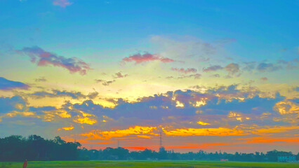 Dramatic sunset sky over rural agricultural fields with orange and blue colors reflecting through thick storm clouds creates colorful landscape view for scenic environmental photography. © Ymn&Saad