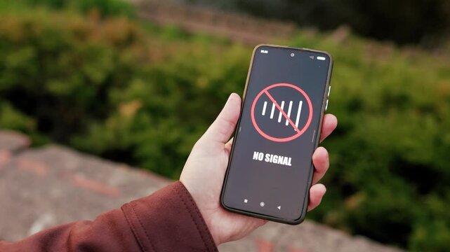 4K video of a hand holding a smartphone outdoors with a No Signal icon on the screen, representing a poor cellular network connection or mobile internet outage. High quality footage