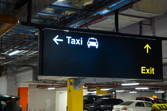 Modern illuminated exit sign mounted on wall in public building, emergency wayfinding system, safety guidance, architectural interior, and evacuation route concept.