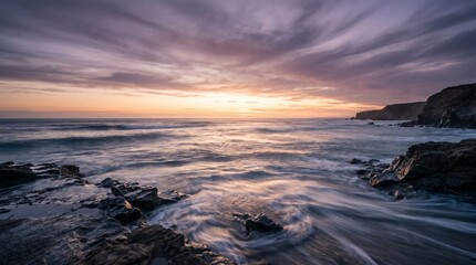 Obraz premium Majestic sunset over a rugged coastline with waves crashing onto the shore, creating a tranquil and serene natural landscape