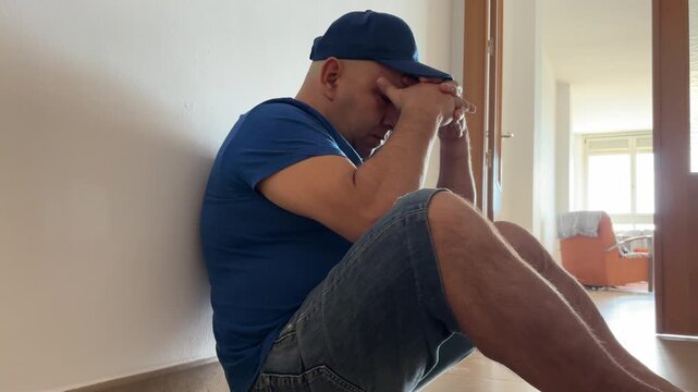 Hombre sentado en el pasillo agobiado y preocupado