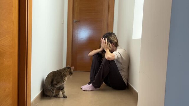 Mujer agobiada en el pasillo con su gato