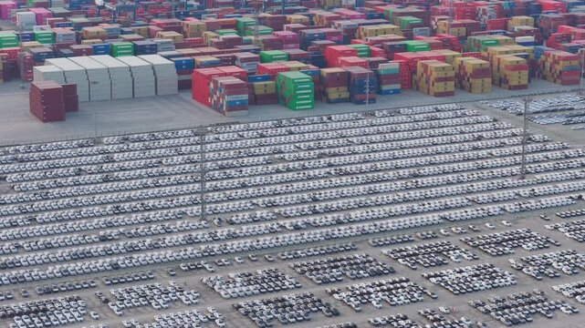 Wide aerial view of vehicle terminal and container yard under cloudy evening sky