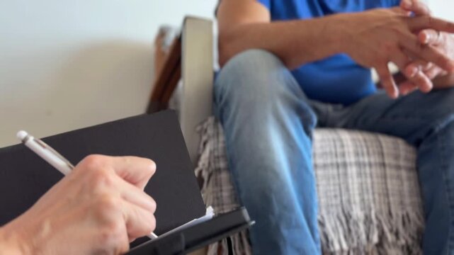 Hombre en consulta de terapia con terapeuta tomando notas