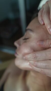 Calm woman receives expert facial massage under gentle ambient lighting