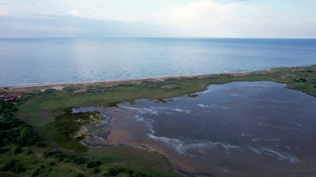 Aerial view of the Shabla Lake wetlands and the sandy beach strip along the Black Sea coast under a soft sky in Shabla, Dobrich Province, Bulgaria.