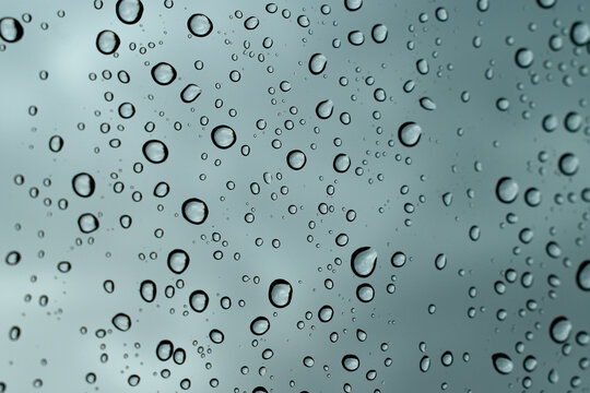 Rain drops close up on window glass outdoors. Droplets on the glass. Water drop texture background. 