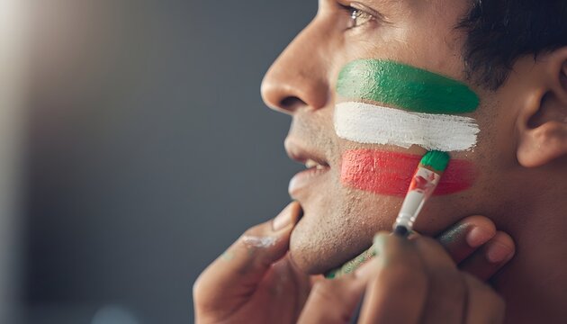 Aficionado pint&aacute;ndose la cara con franjas verde, blanca y roja antes de un evento deportivo