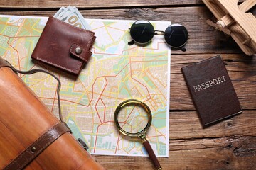 Naklejka premium Planning trip. Map, wallet with money, passport, sunglasses and magnifying glass on wooden background, flat lay