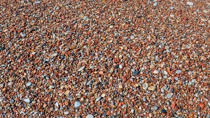 Plakat Colorful sea pebbles texture background on a beach. Top view flat lay of wet multi colored stones and small gravel for summer vacation concept, spa therapy, abstract natural pattern 