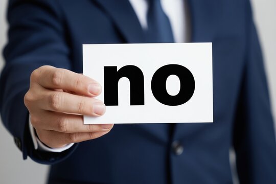 Man in suit shows card with word no. Firm decision, assertive gesture, corporate refusal, clear disagreement, business rejection. Man says no.