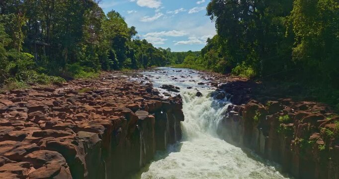 Aerial view of Tad Pha Suam Waterfall near Pakse in Champasak Southern Laos. Water flows over unique column like rock formations surrounded by lush tropical forest, creating a scenic natural