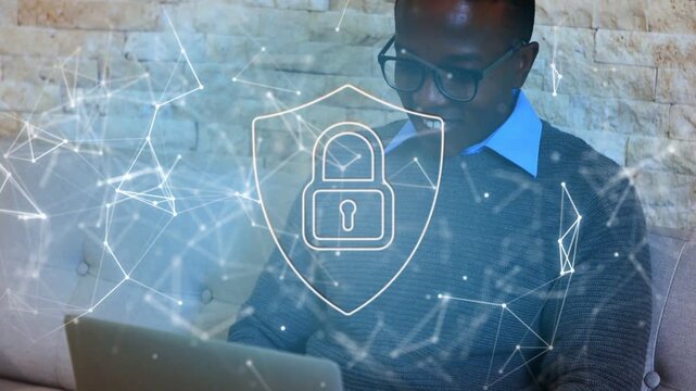 Man typing on laptop on sofa, activating cyber-security shield with drifting nodes protecting data