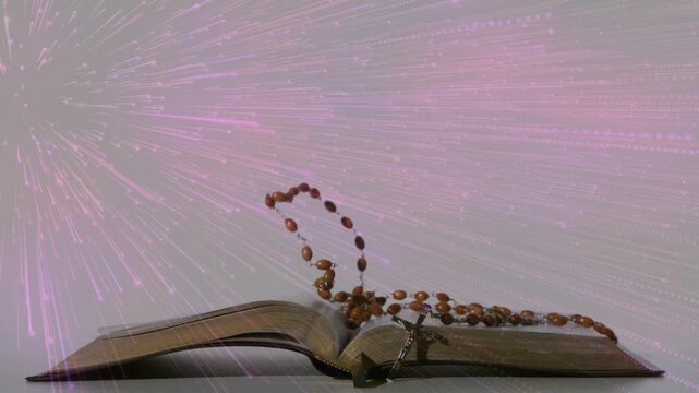 Rosary beads dropping, swinging, sliding onto book pages, curling, settling to rest with pink burst