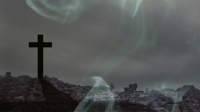 Thin wisps rising, smoke curling and thickening across rocky hill, revealing cross, creating mood