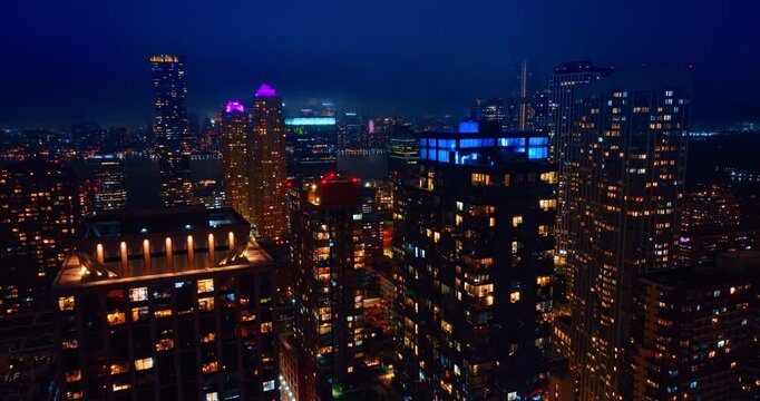Jersey City residential towers and downtown lights at night. Elevated night view of Jersey City towers, apartments, lit windows, streets, and waterfront skyline background
