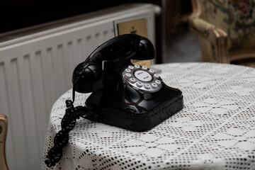 ozdobny czarny telefon na korbkę. zabytkowy telefon na stole 