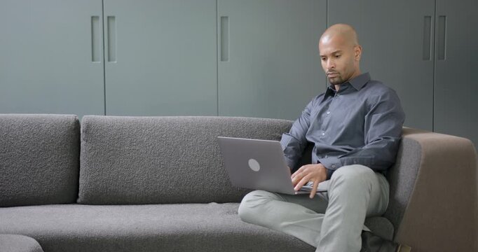 Businessman on Sofa at Home using Laptop