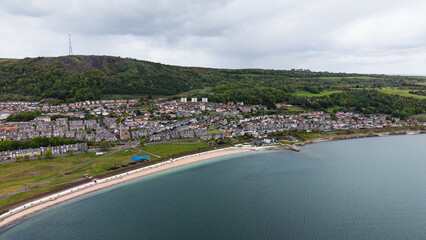 Fototapeta premium Aerial view of Burntisland beach and coastal town in Fife. Scenic sandy shoreline and residential architecture overlooking the Firth of Forth, Scotland.