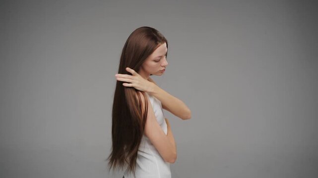 Attractive young woman running fingers through long healthy brunette hair