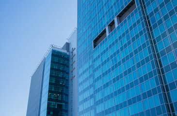 Obraz premium Skyscrapers in the city and blue sky background close up. Minimalistic architecture made of glass, tall buildings, business and finance, construction industry.
