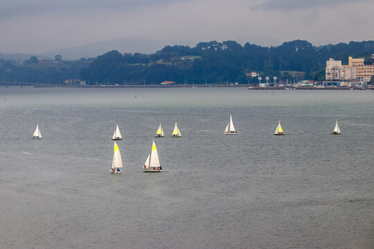 A group of small sailboats in the bay of Santander, Cantabria, Spain, on a cloudy summer day.
