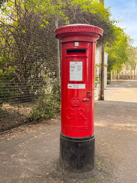 Red British Postbox on City Street Vintage Pillar Mailbox with GR Emblem and Priority Label