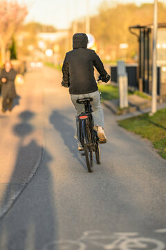 Cyclist riding bicycle along urban road during golden hour commute.