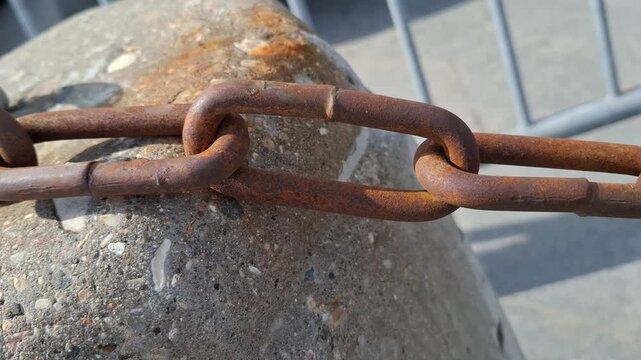 Heavy rusty iron chain lying on a weathered concrete block outdoors. Close-up view of old oxidized metal links and rough cement surface, ideal for industrial, security, and vintage grunge concepts