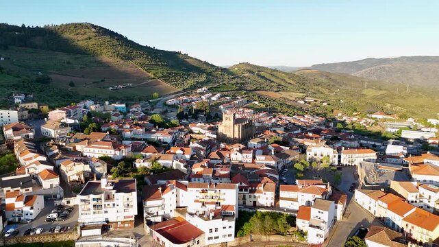 Aerial view of Basilica Menor de Nossa Senhora da Assuncao and the historic town center with terracotta rooftops and green hills in Torre de Moncorvo, Braganca, Portugal.