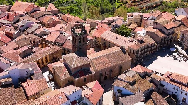 Aerial view of Church of Our Lady of the Assumption surrounded by red-tiled rooftops and terraced hills in Fermoselle, Castilla y Leon, Spain.