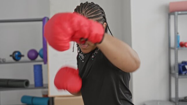 Man with red boxing gloves in a studio throws a straight jab with fists up and defensive guard, training in a boxing gym; determination.