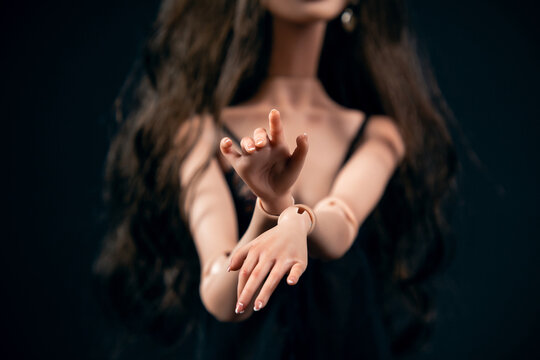 Hinged doll on a black background. Beautiful female hands closeup.