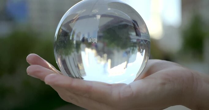 Hand Holding Glass Sphere in Urban Park Setting