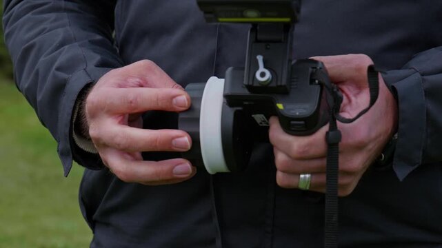 Professional Focus Puller Hands Using Remote Follow Focus on Film Set