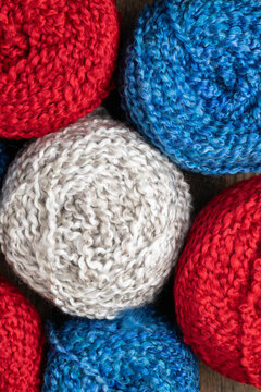 Balls or spools of yarn for knitting or crocheting. Red, white, gray, blue, vertical