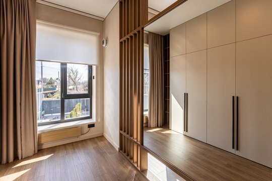 Modern bedroom interior with wooden slat partition and built-in wardrobe