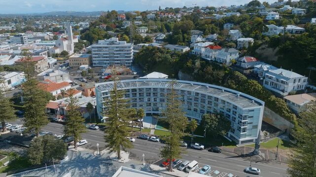 Aerial view of the Scenic Hotel Te Pania, a landmark building, in Napier, New Zealand. The hotel offers accommodation and dining, attracting tourists to the city. Houses on the hill in the background.