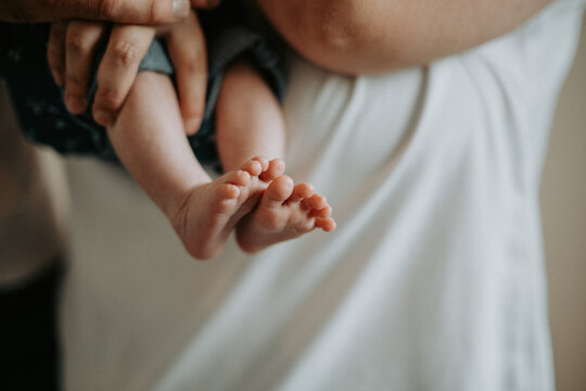 Petits pieds de nouveau-n&eacute; dans les mains de ses parents