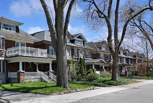 Tree-lined street of three story brick houses with dormer windows