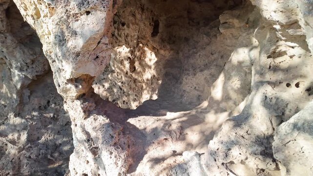 Natural tufa stone cliff face with eroded surface and dramatic shadows on sunny day Antalya.