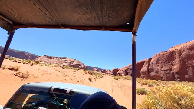 Tourist's point of view driving on a jeep safari through the scenic red sand desert landscape of monument valley navajo tribal park, enjoying an adventurous guided tour in arizona