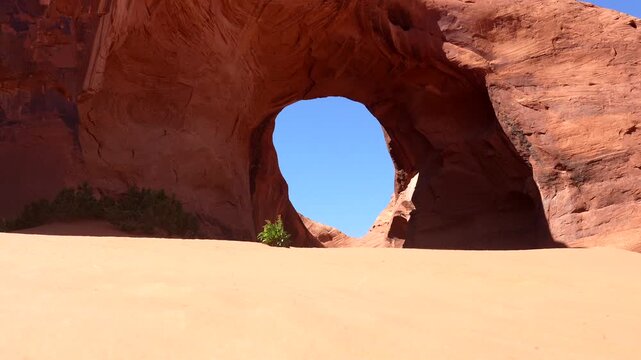 Monumental sandstone rock formation, the ear of the wind arch, standing against a bright blue sky in the iconic desert landscape of monument valley tribal park on the arizona utah border