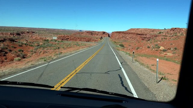 Point of view shot from a moving vehicle driving along scenic highway 163, heading towards the iconic forrest gump point viewpoint with the majestic red rock buttes of monument valley, utah