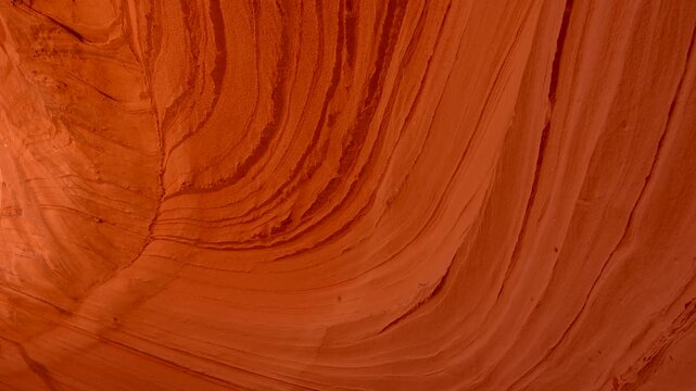 Scenic view from inside the stunning red rock formations of biidi the arch cave, revealing its famous swirling sandstone patterns and layers against a bright blue sky in page, arizona